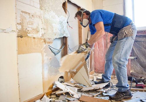 Man tearing out old kitchen during home renovations.
